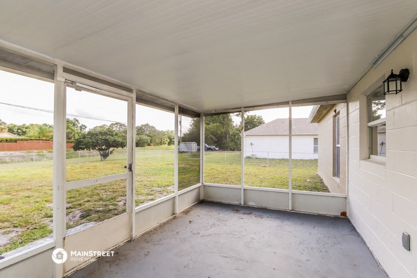 a screened in porch with a view of a field and a house