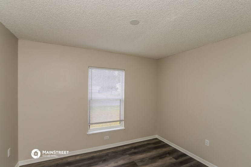 the interior of a bedroom with a window and wooden floors