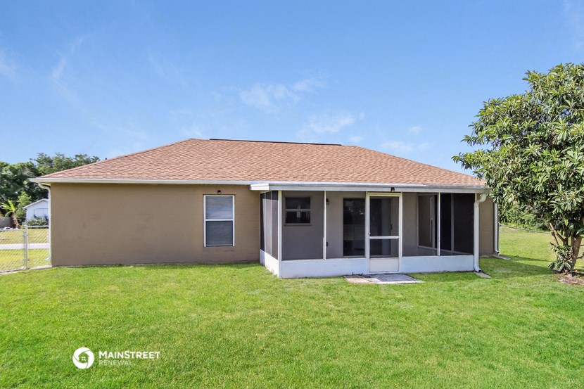 a small brown house with a lawn and a tree