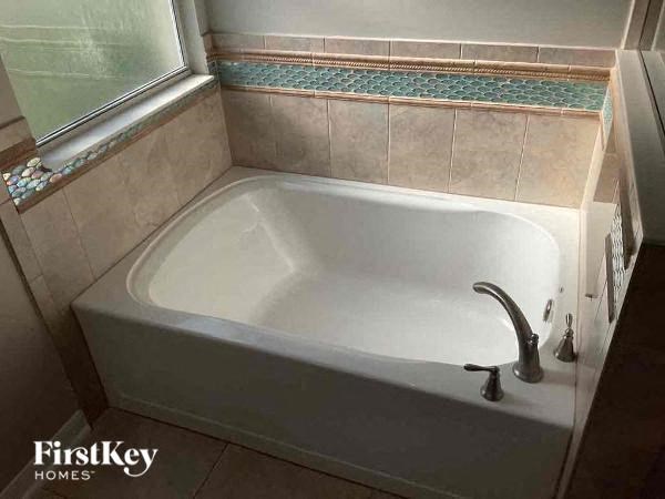 a white bath tub in a bathroom with a window