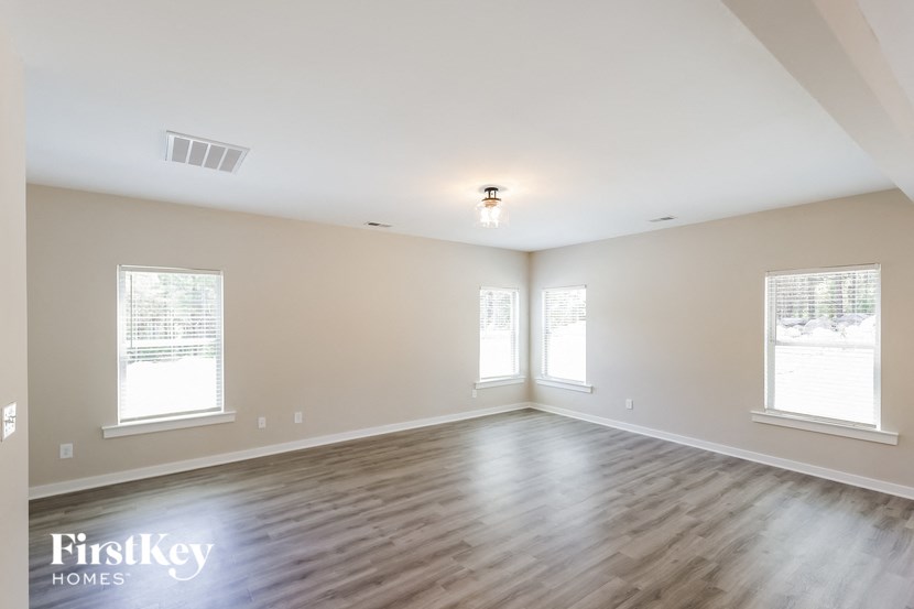 the spacious living room with hardwood flooring and three windows
