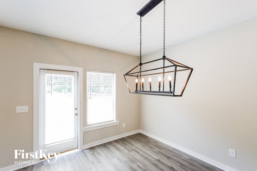 the living room of an empty home with a chandelier and a door to