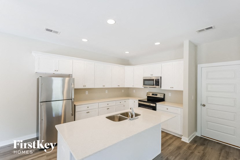 a white kitchen with white cabinets and stainless steel appliances