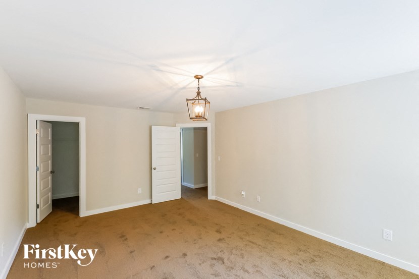 a empty living room with a light fixture and a door to a closet