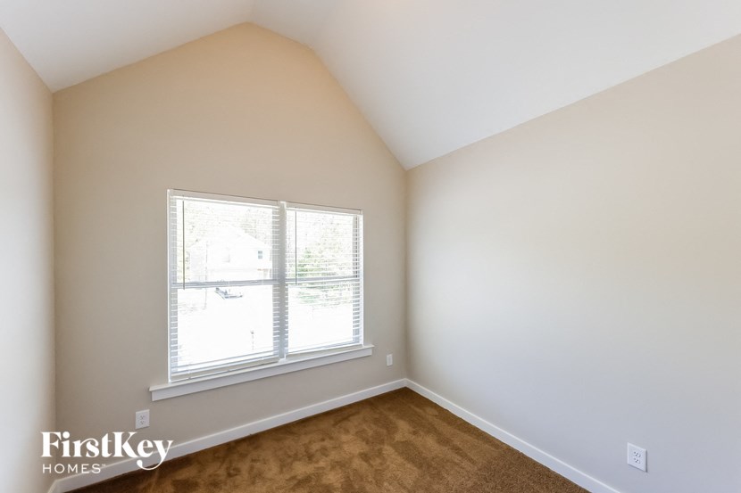 a bedroom with a large window and a brown carpet