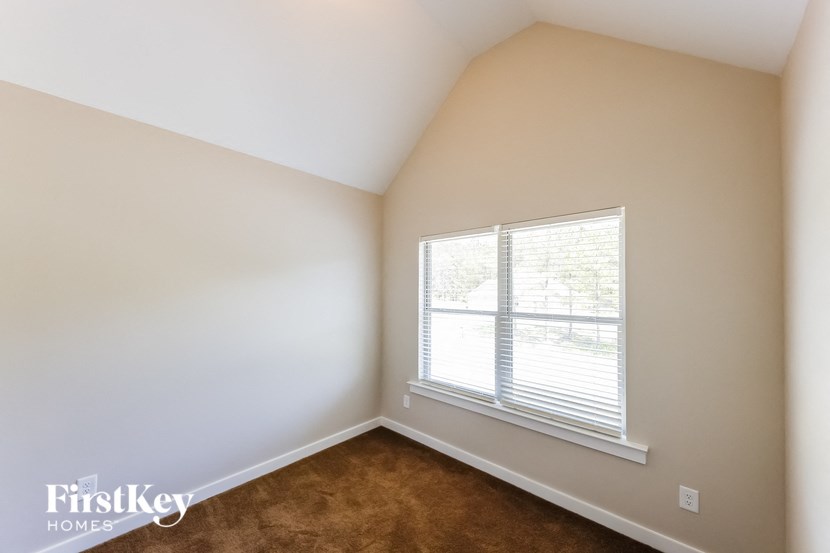 a bedroom with a large window and a brown carpet