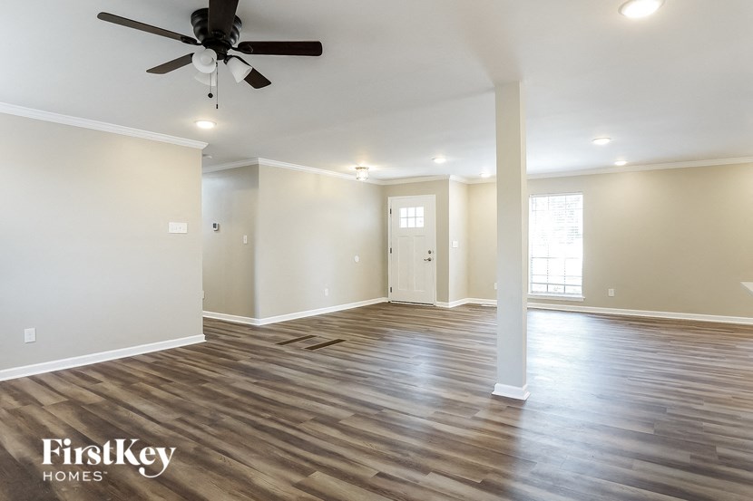 the spacious living room with hardwood flooring and a ceiling fan