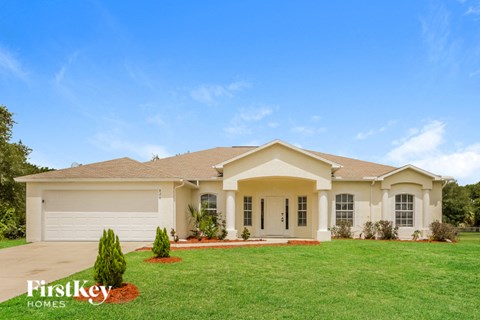 a beige house with a lawn in front of it