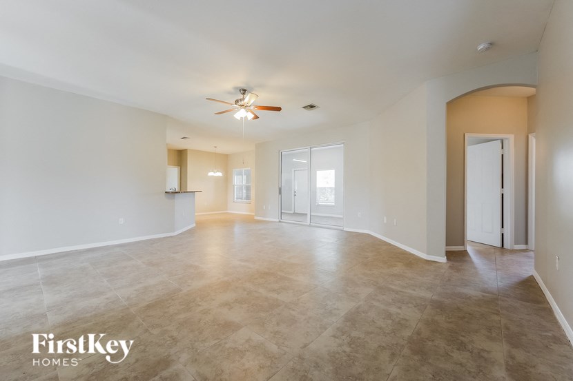 an empty living room and kitchen with a ceiling fan