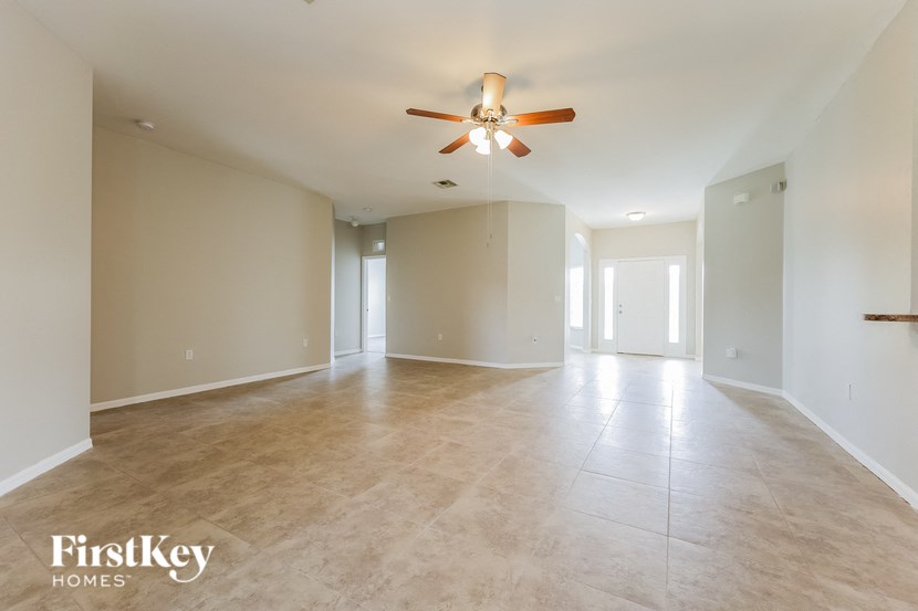 a empty living room with a ceiling fan and a tiled floor