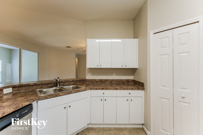 a kitchen with white cabinets and granite counter tops and a sink