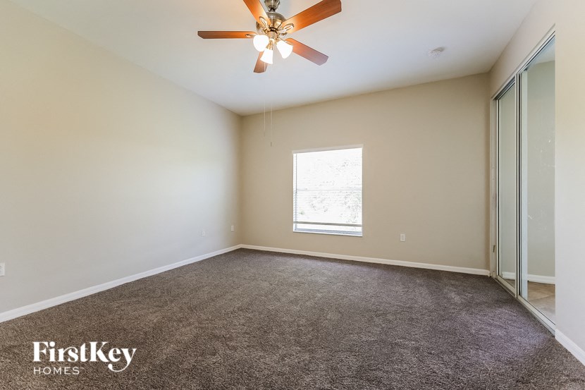 an empty living room with a ceiling fan and a window