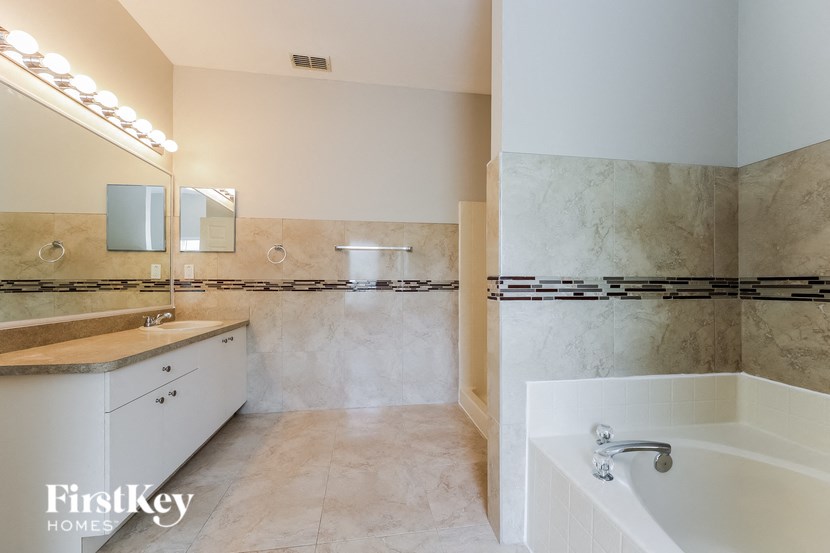 a large bathroom with a tub and a sink and a mirror