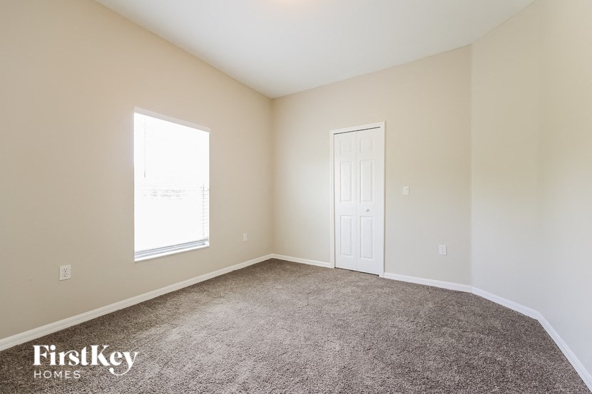 a carpeted room with a white door and a window