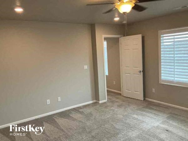 a empty living room with a ceiling fan and a door