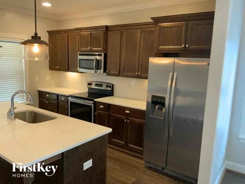 A kitchen with a stainless steel refrigerator and wooden cabinets.