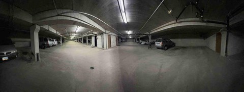 A parking garage with a few cars and a truck.