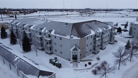 A large building with a grey roof is surrounded by snow.