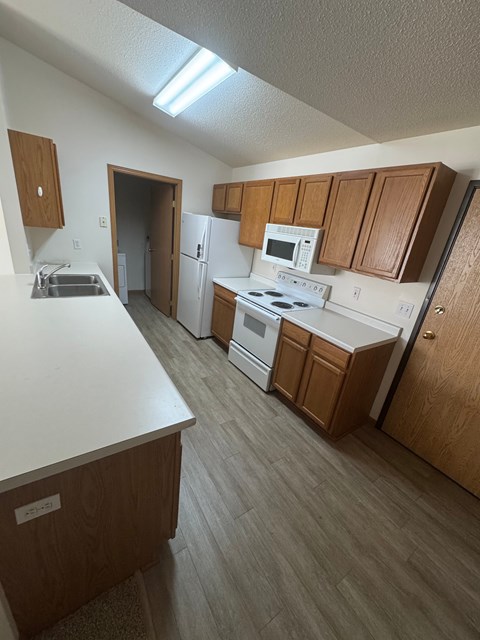A kitchen with a white counter top and wooden cabinets.