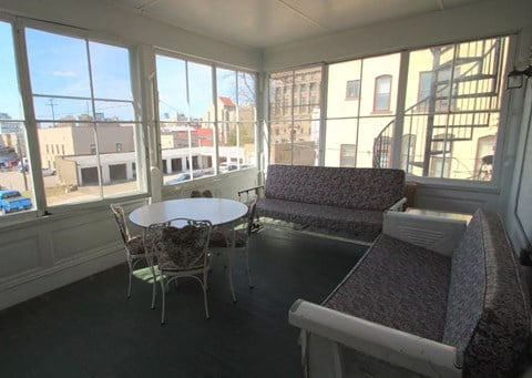 a living room with a table and chairs and large windows
