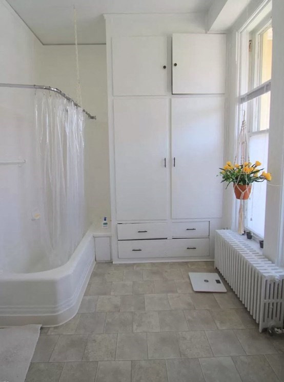 a white bathroom with a tub and a window