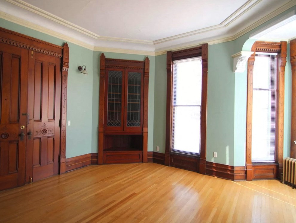 an empty room with a wooden floor and a door and windows