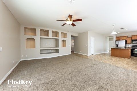 A spacious living room with a ceiling fan and built-in shelves.