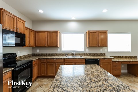 A kitchen with granite countertops and wooden cabinets.