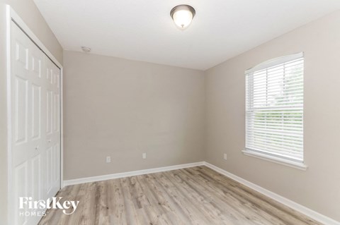an empty bedroom with wood flooring and a white door