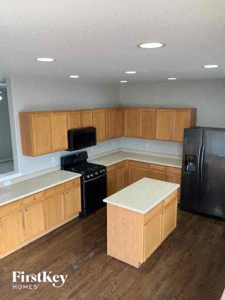 a kitchen with wooden cabinets and a black refrigerator