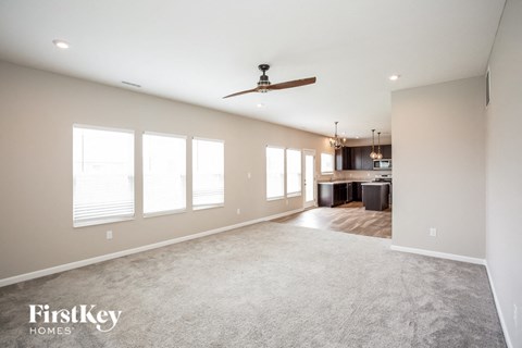 A spacious room with a ceiling fan and large windows.