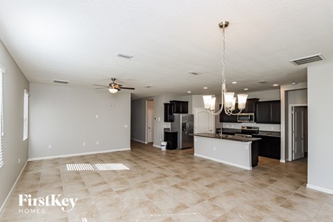 A spacious kitchen and living room with a tile floor and a chandelier.