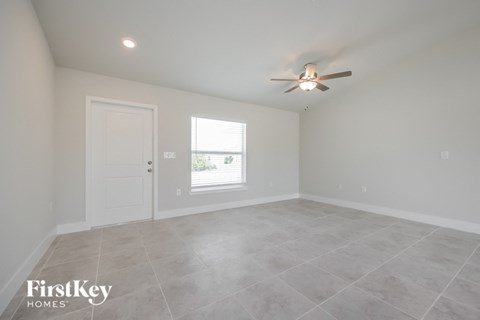 an empty living room with a ceiling fan and a window