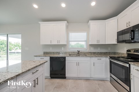 a kitchen with white cabinets and black appliances