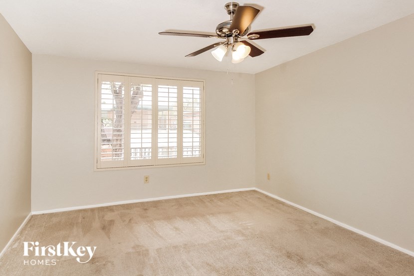 a empty living room with a ceiling fan and a window