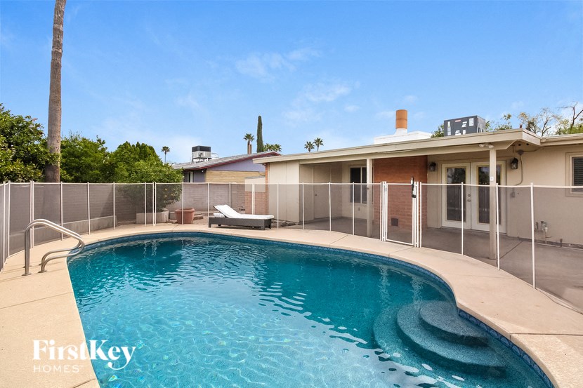 a large pool in front of a house with a fence around it