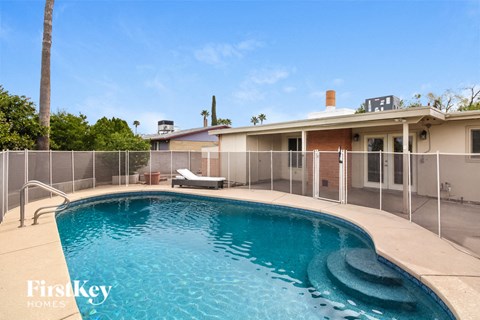 a large pool in front of a house with a fence around it