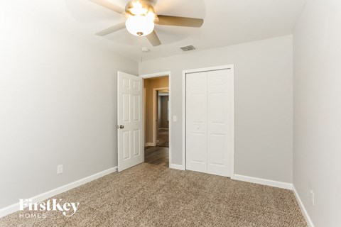 a bedroom with a ceiling fan and a door to a hallway