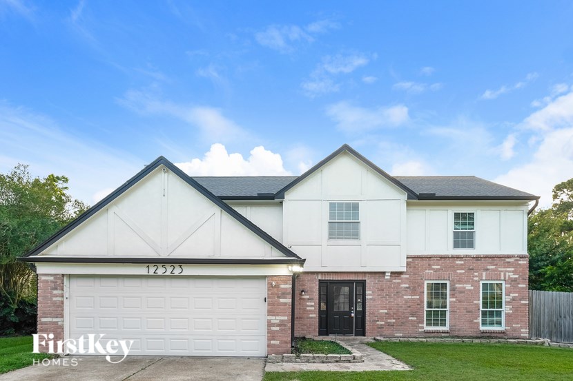 A two-story house with a garage and a brick wall.