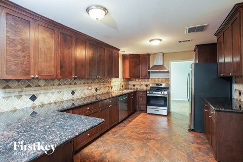 A kitchen with brown cabinets and a black refrigerator.