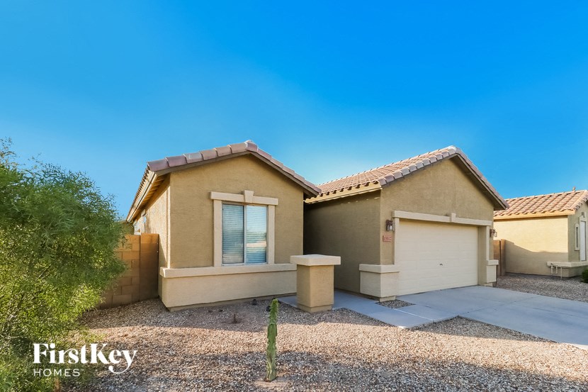 a beige house with a driveway and a cactus