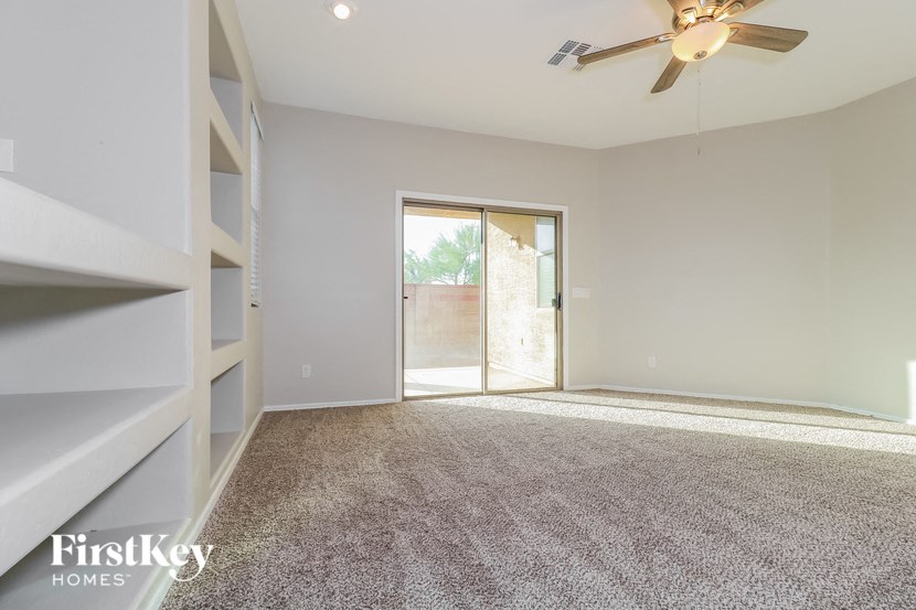 an empty living room with a ceiling fan and a door to a patio