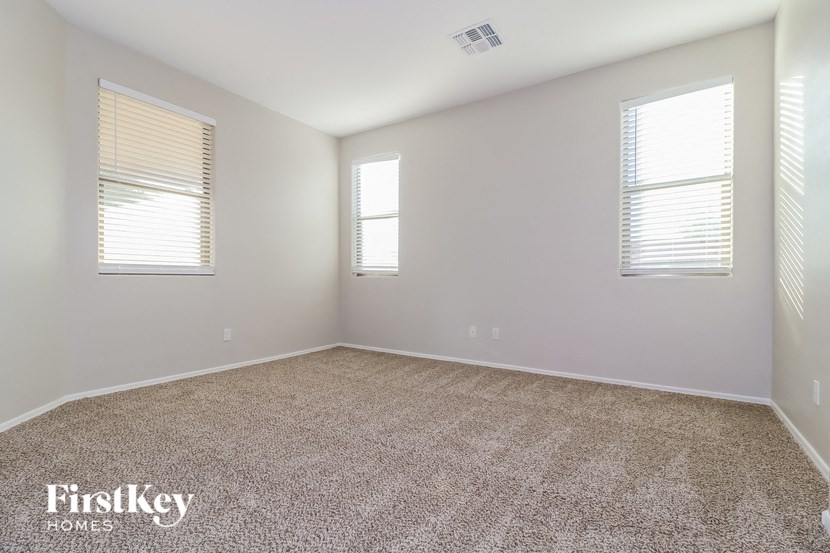 a empty room with carpet and two windows