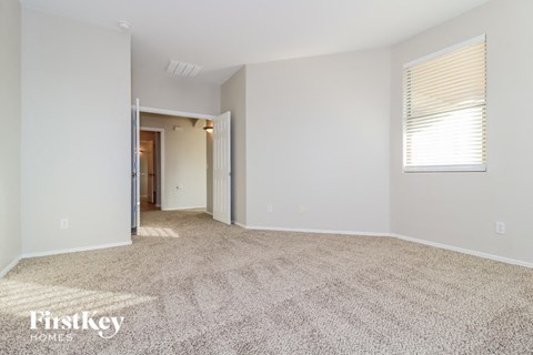 a spacious living room with carpet and a door to a hallway