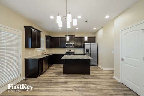 A kitchen with dark wood cabinets and a granite countertop.