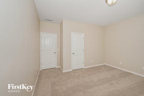 A bedroom with two doors and a carpeted floor.