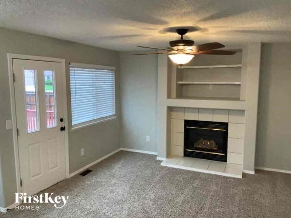 a living room with a fireplace and a ceiling fan