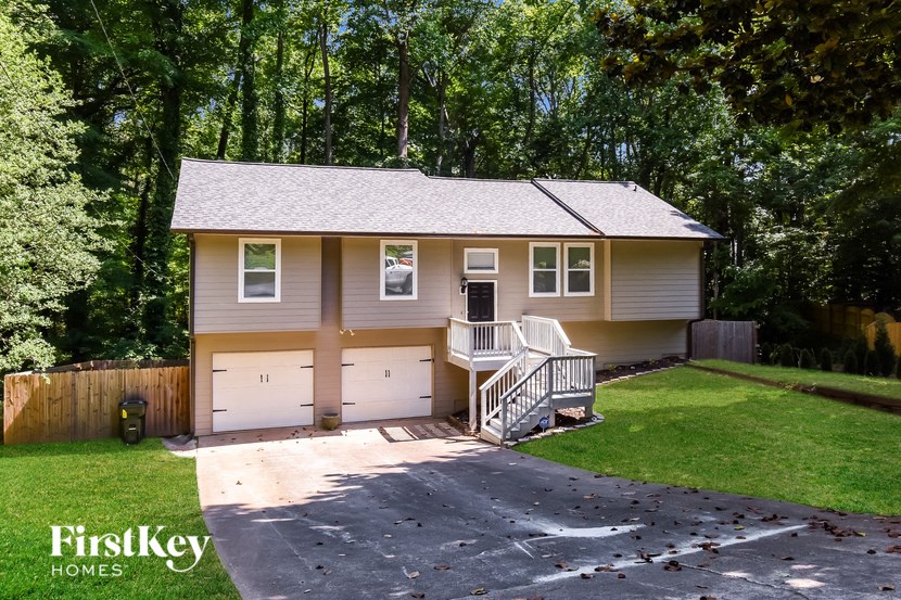 A house with a garage and a driveway is surrounded by trees.