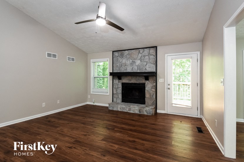 A room with a stone fireplace and wood flooring.
