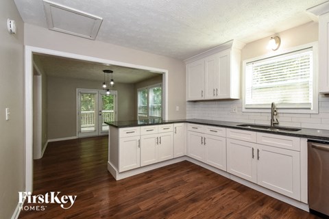 A kitchen with white cabinets and a wooden floor.